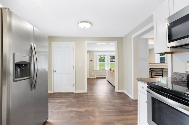 kitchen with dark stone counters, baseboard heating, dark wood-type flooring, white cabinetry, and stainless steel appliances