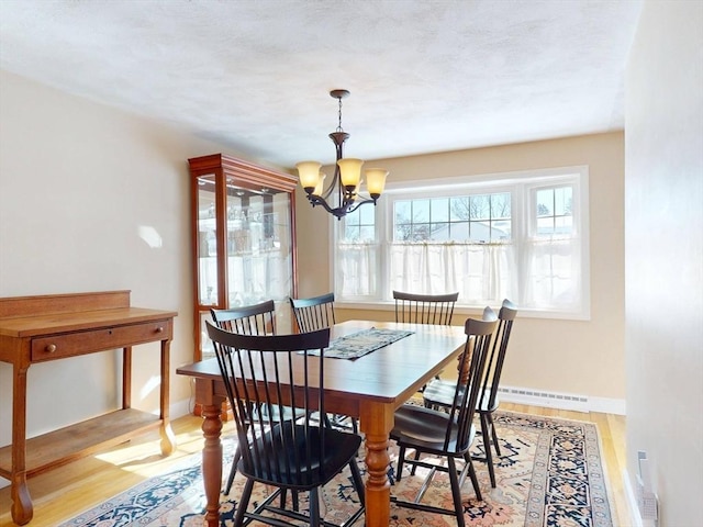 dining room featuring a chandelier, baseboards, visible vents, and light wood-style floors