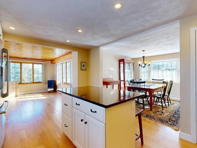 kitchen featuring dark countertops, light wood-type flooring, white cabinets, and a center island