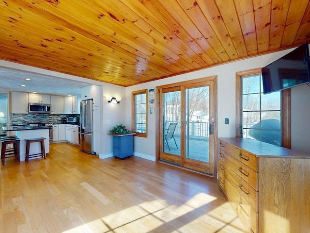 interior space with light wood finished floors, wood ceiling, and baseboards