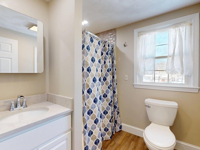 bathroom with curtained shower, toilet, wood finished floors, vanity, and baseboards