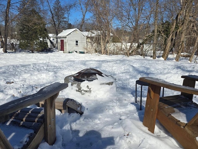 yard layered in snow with an outbuilding, a fire pit, and a storage shed