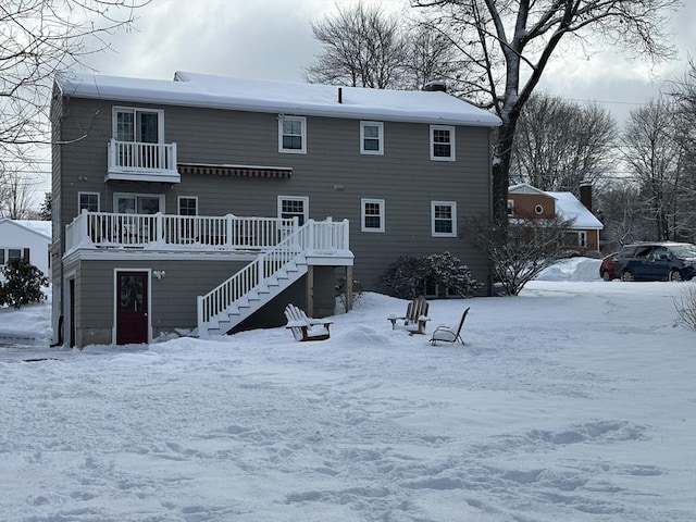 snow covered property featuring stairway and a balcony