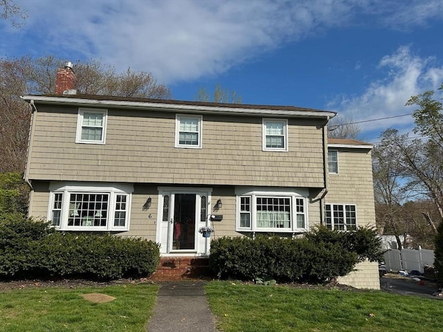 colonial inspired home with a front lawn and a chimney