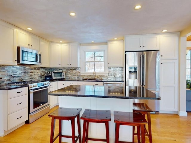 kitchen featuring stainless steel appliances, light wood-style floors, a sink, and a breakfast bar area