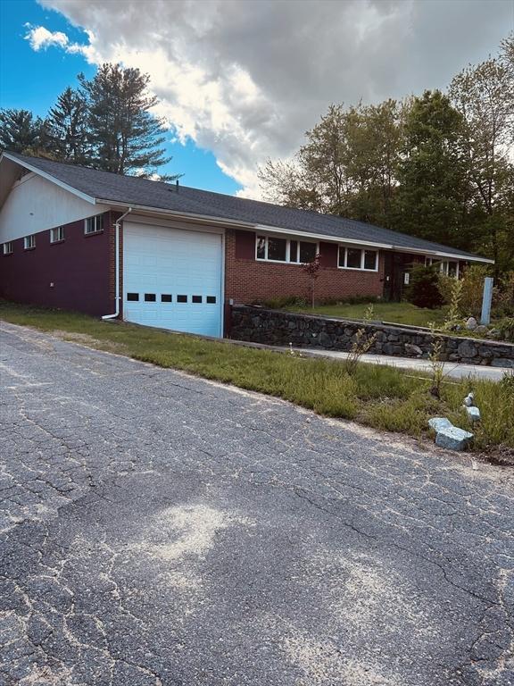 ranch-style home with an attached garage, brick siding, and driveway