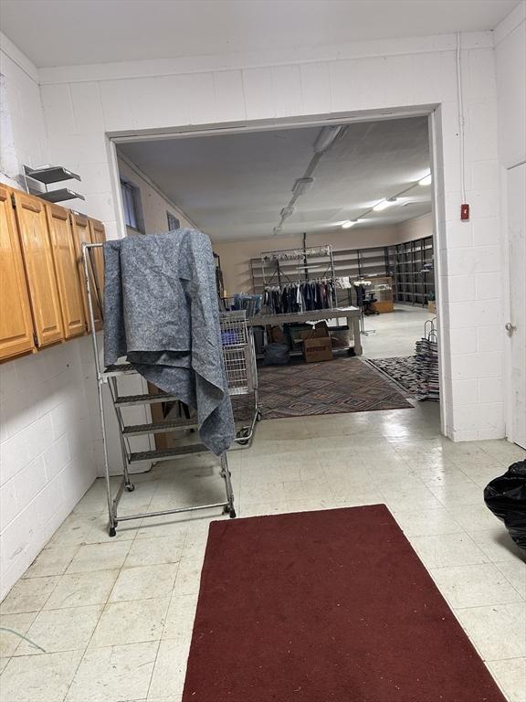 misc room with light floors and concrete block wall