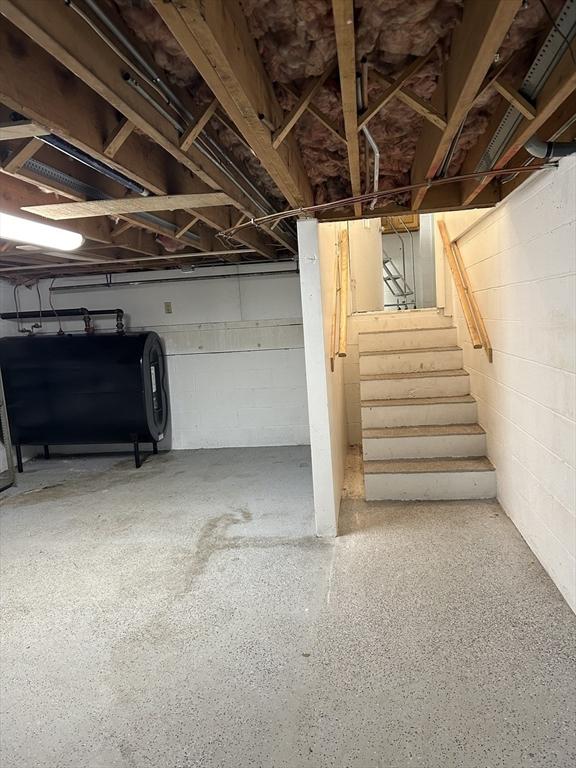 below grade area with oil tank, stairway, and concrete block wall