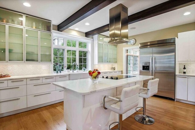 32 Twitchell St, Wellesley, MA 02482 - kitchen with built in fridge, black electric stovetop, tasteful backsplash, beamed ceiling, and white cabinetry