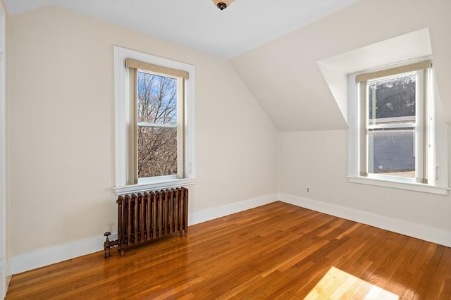 bonus room with hardwood / wood-style flooring, radiator heating unit, and vaulted ceiling