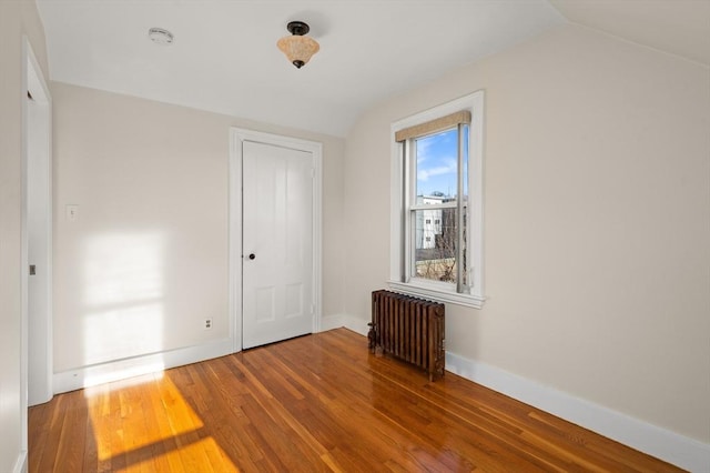 interior space featuring a closet, vaulted ceiling, radiator heating unit, and hardwood / wood-style floors