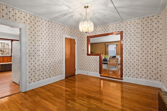 empty room featuring ornamental molding, hardwood / wood-style floors, plenty of natural light, and an inviting chandelier