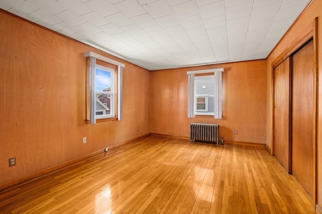 empty room with radiator heating unit and light wood-type flooring