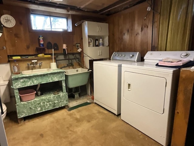 washroom with wooden walls, sink, and washer and dryer