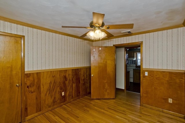 spare room featuring ceiling fan, ornamental molding, and wood-type flooring