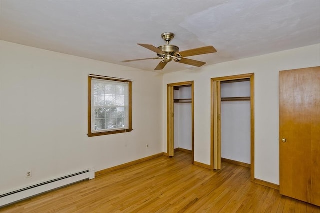 unfurnished bedroom featuring a baseboard radiator, two closets, ceiling fan, and light wood-type flooring