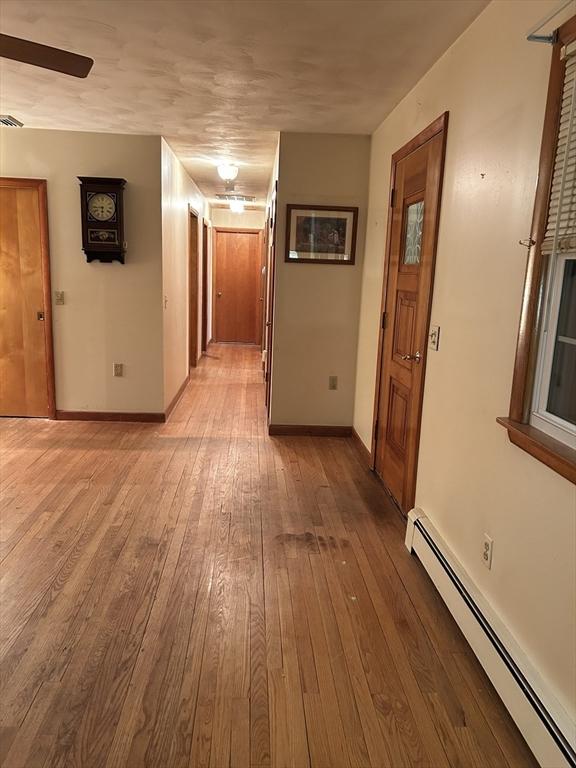 hallway with a baseboard radiator and light hardwood / wood-style floors