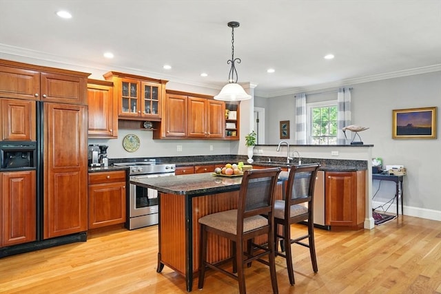 149 Acorn St, Marshfield, MA 02050 - kitchen with stainless steel range, paneled fridge, a peninsula, brown cabinetry, and a breakfast bar area