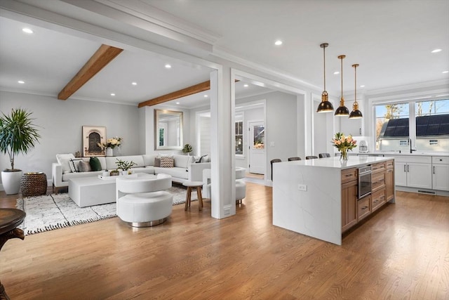 kitchen with pendant lighting, light hardwood / wood-style flooring, white cabinetry, beam ceiling, and a kitchen island