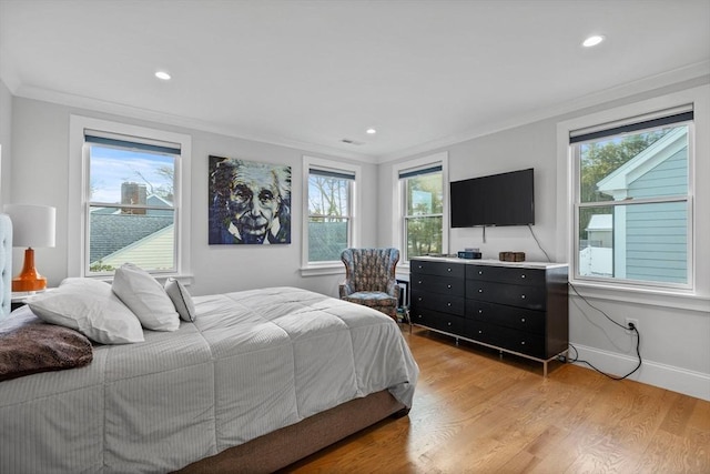 bedroom with ornamental molding and light hardwood / wood-style floors