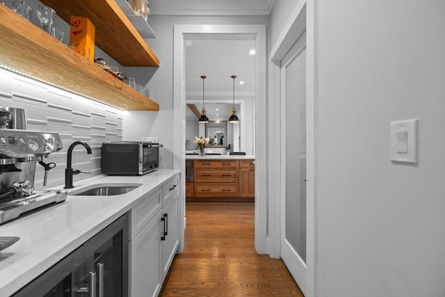 kitchen with pendant lighting, white cabinetry, sink, dark hardwood / wood-style flooring, and light stone countertops