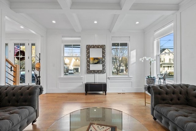 living room featuring coffered ceiling, a healthy amount of sunlight, beam ceiling, and light hardwood / wood-style floors