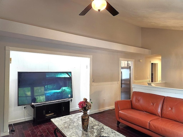 living area featuring a ceiling fan, dark wood-type flooring, baseboards, wainscoting, and vaulted ceiling