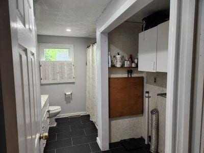 full bathroom featuring toilet, vanity, tile patterned floors, and baseboards