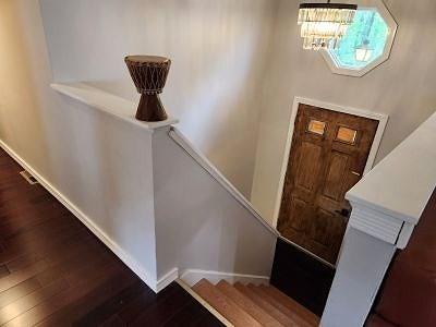 foyer entrance with wood finished floors, baseboards, and a chandelier