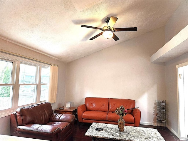 living room featuring lofted ceiling, a textured ceiling, baseboards, dark wood-style flooring, and ceiling fan