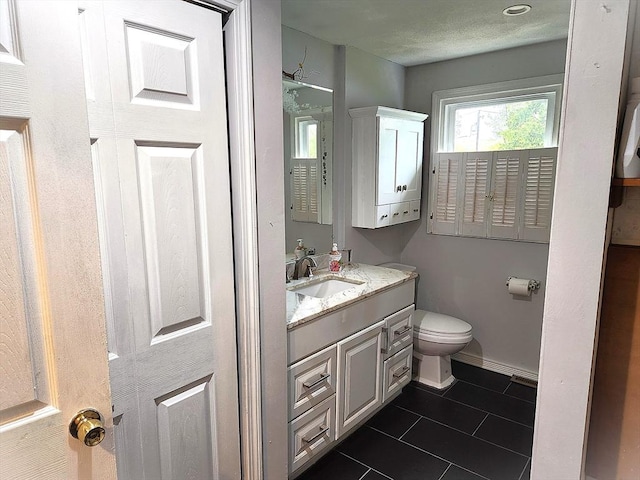 half bath with toilet, tile patterned flooring, vanity, and baseboards