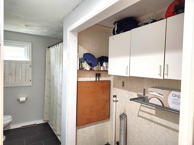 interior space with toilet, tile patterned flooring, visible vents, and baseboards