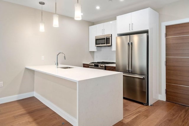 425 Lagrange St Unit 107, Boston, MA 02132 - kitchen with stainless steel appliances, a sink, light wood finished floors, a peninsula, and recessed lighting