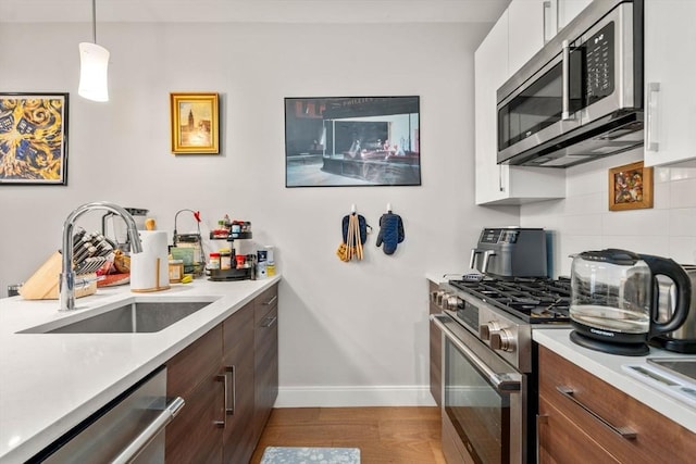 425 Lagrange St Unit 107, Boston, MA 02132 - kitchen with appliances with stainless steel finishes, a sink, baseboards, light countertops, and backsplash