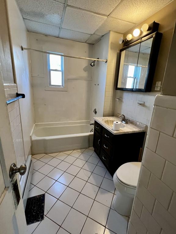 full bathroom featuring a drop ceiling, vanity, bathtub / shower combination, tile patterned floors, and toilet