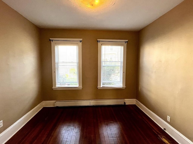 unfurnished room featuring baseboard heating and dark wood-type flooring