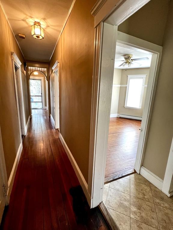 hall featuring hardwood / wood-style floors, baseboard heating, and crown molding