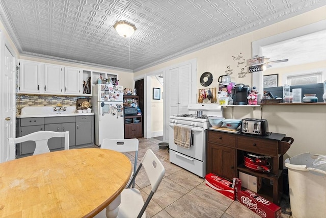 kitchen with white appliances, white cabinetry, ornamental molding, light tile patterned flooring, and decorative backsplash