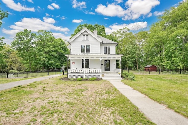 victorian home featuring covered porch, a chimney, and view of wooded area