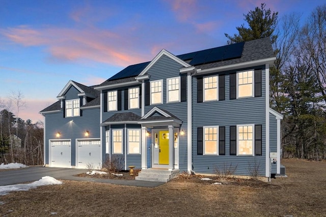 view of front of property with driveway, a garage, and roof mounted solar panels