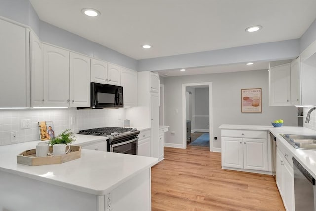 100 Summit, Brookline, MA 02446 - kitchen featuring stainless steel appliances, a sink, a peninsula, backsplash, and white cabinetry