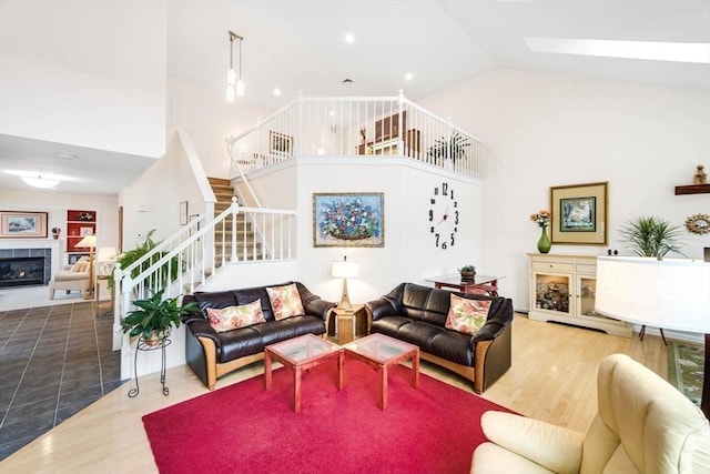 living room with hardwood / wood-style flooring, a fireplace, high vaulted ceiling, and a skylight