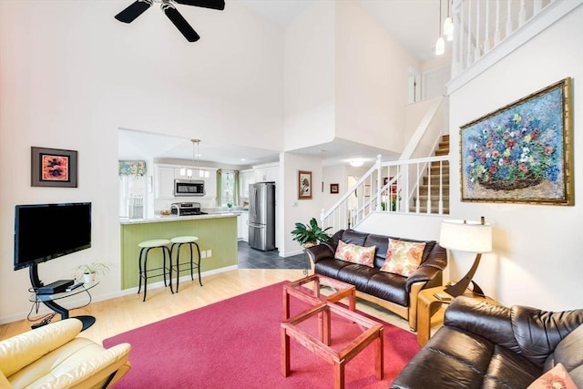 living room featuring ceiling fan, wood-type flooring, and a high ceiling