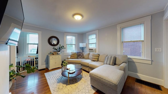 living area featuring baseboards, visible vents, and wood finished floors