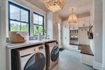 laundry area with washing machine and dryer and an inviting chandelier