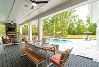 wooden deck with ceiling fan and an outdoor fireplace