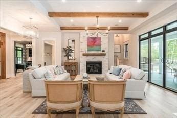 living room with a fireplace, beamed ceiling, and light wood-type flooring