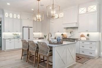 kitchen featuring decorative light fixtures, white fridge, a kitchen breakfast bar, and white cabinetry