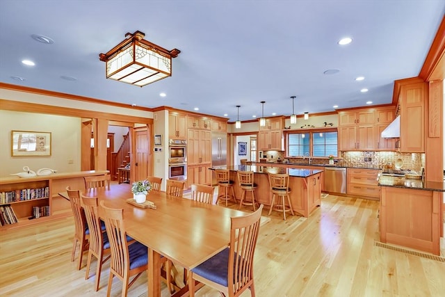 dining space with sink, crown molding, and light hardwood / wood-style floors