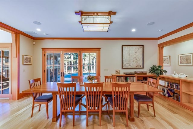 dining room with french doors, crown molding, and light hardwood / wood-style flooring